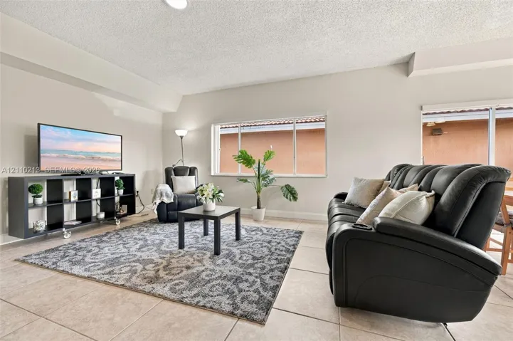Neutral-toned interior space featuring ceramic tile flooring, expansive windows, and a sliding glass door