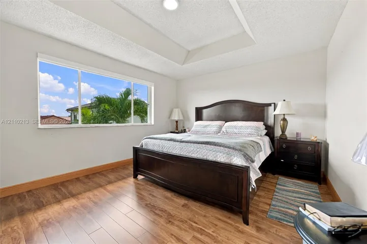 Room featuring a tray ceiling, wood-finish flooring, and a large horizontal window