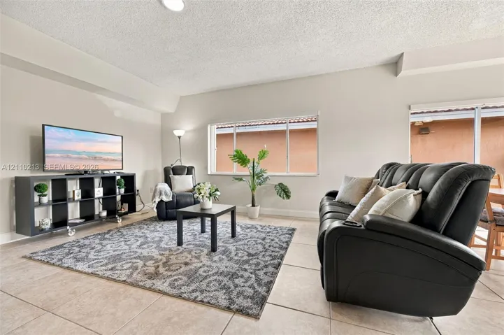 Neutral-toned interior space featuring light-colored ceramic tile flooring, horizontal sliding windows, and a sliding glass door providing access to the exterior