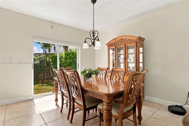 Dining area featuring large-format ceramic tile flooring, a multi-arm metal chandelier, and a sliding glass door providing external access