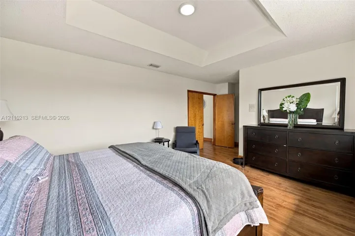 Room featuring a tray ceiling, recessed lighting, and wood-finish flooring with solid-core wood doors