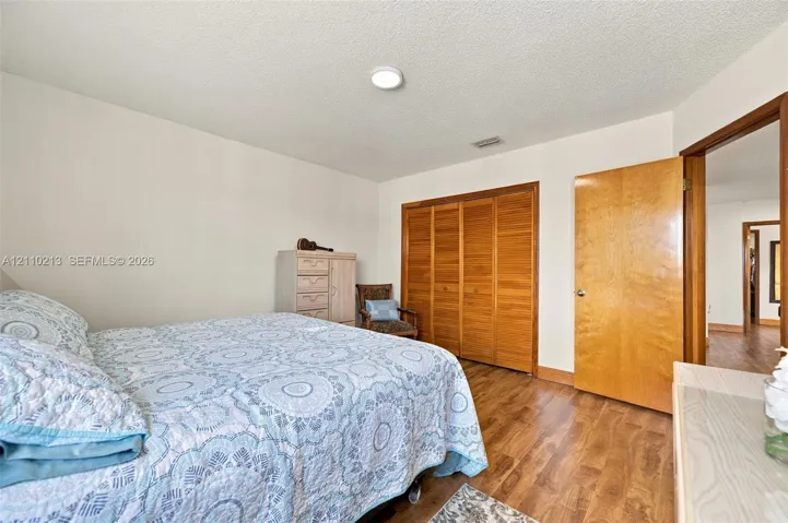 Room featuring wood-finish flooring, wood-toned bi-fold closet doors, a matching interior door, and a recessed ceiling light fixture