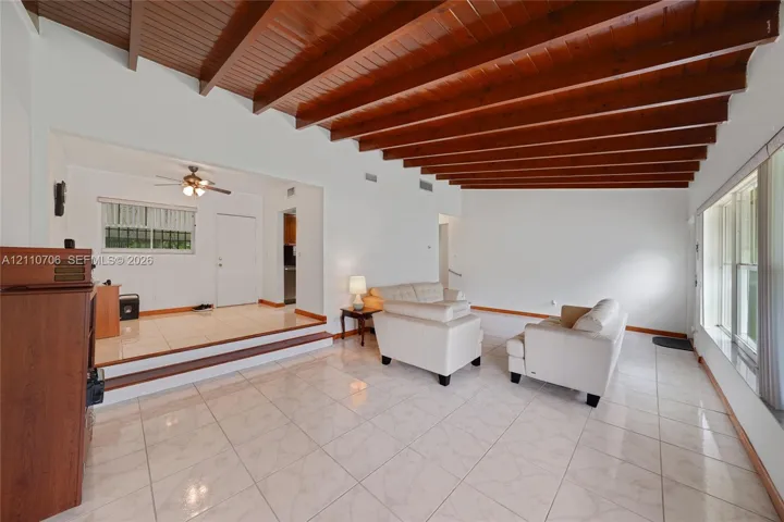 Exposed wood-beam ceiling, large-format ceramic tile flooring, and oversized windows providing natural light