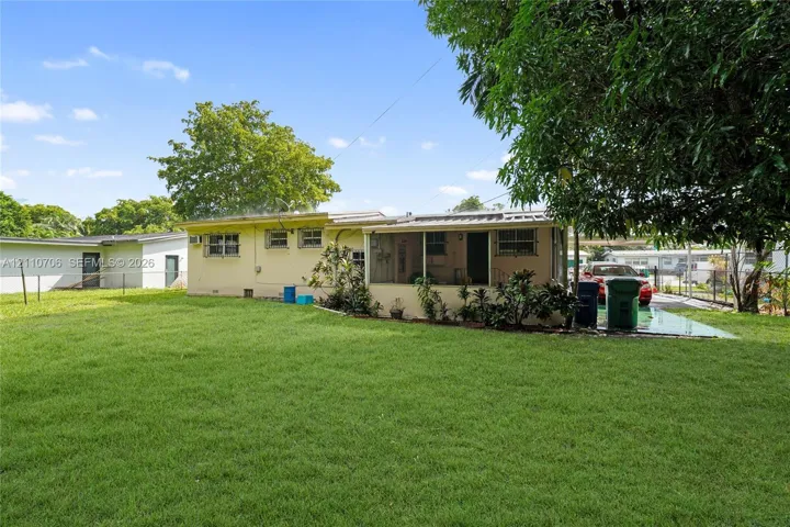 Expansive backyard featuring a level lawn, mature trees, a screened-in porch, and a metal roof