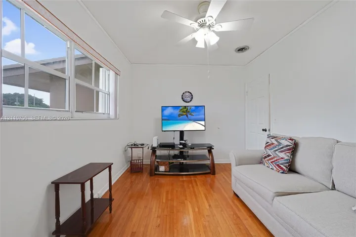 Wood-finish flooring, multi-pane windows, and a ceiling-mounted light fixture with integrated fan