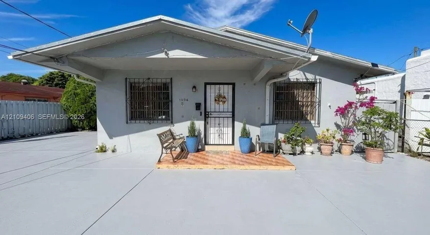 Exterior facade featuring a covered entryway, tiled porch, concrete surface, and metal security bars on the windows