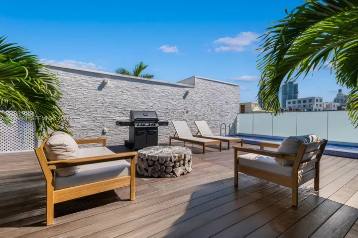 Rooftop terrace featuring wood-finish decking, a textured stone accent wall, and a perimeter glass railing system