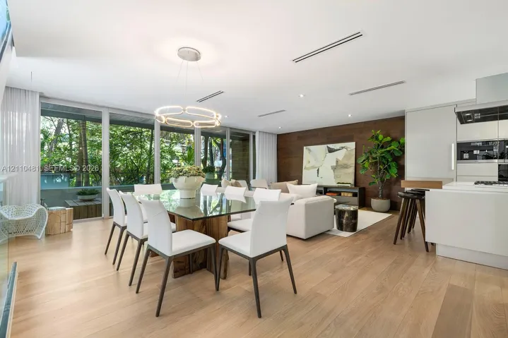 Open-concept living space featuring wood-finish flooring, floor-to-ceiling windows, a wood-paneled accent wall, and recessed linear lighting