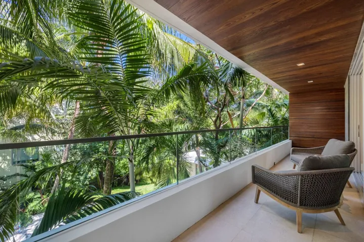 Covered balcony featuring wood-paneled ceiling, glass panel railing, and stone tile flooring