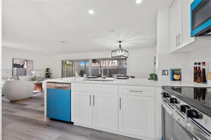 Kitchen featuring white cabinetry, quartz countertops, a stainless steel undermount sink, and wood-finish flooring