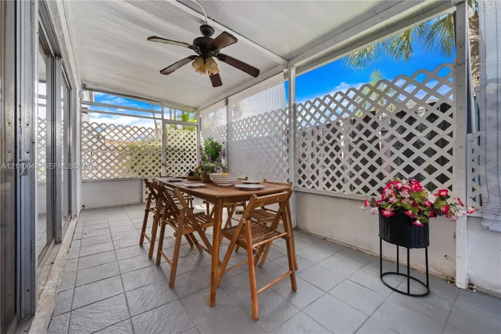 Covered patio featuring ceramic tile flooring, built-in ceiling fan with integrated lighting, and white lattice privacy screening