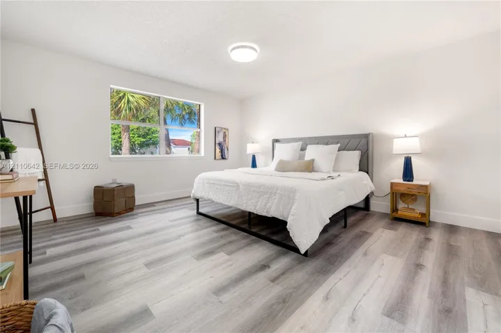 Neutral-toned interior space featuring wood-finish flooring, a large window, and a flush-mount ceiling fixture