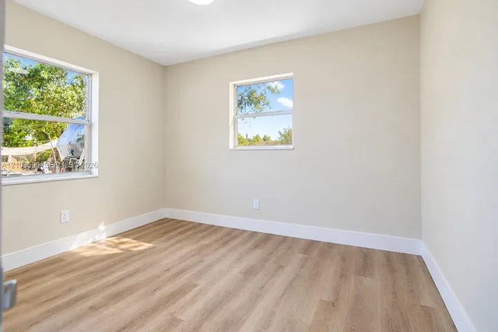Interior space featuring neutral-toned walls, wood-finish flooring, and two dual-pane windows