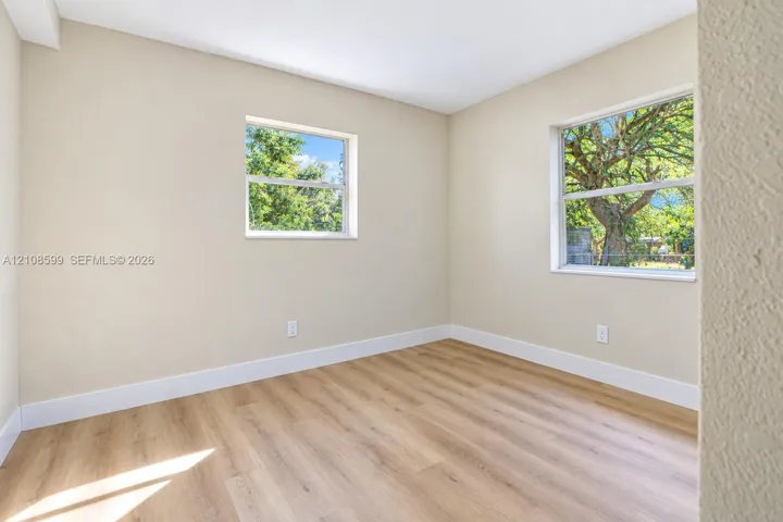 Neutral-toned interior space featuring wood-finish flooring, dual windows, and smooth wall finishes