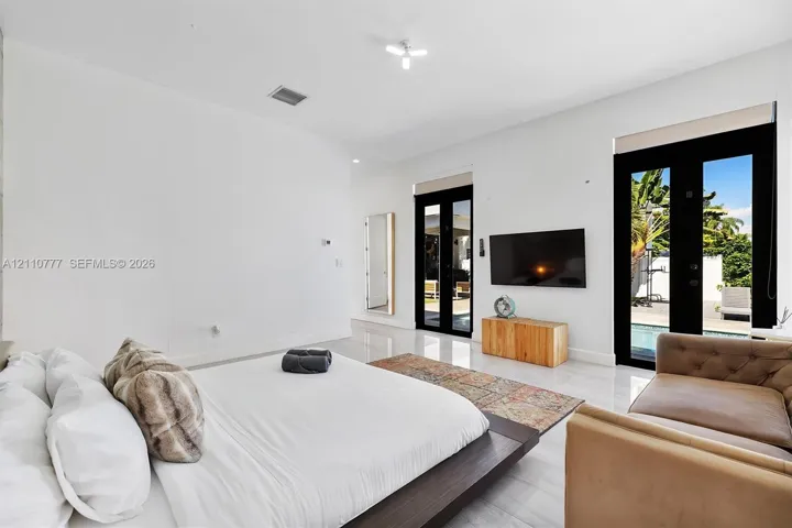 Polished large-format tile flooring, high ceilings, and double glass-paneled exterior doors with black frames