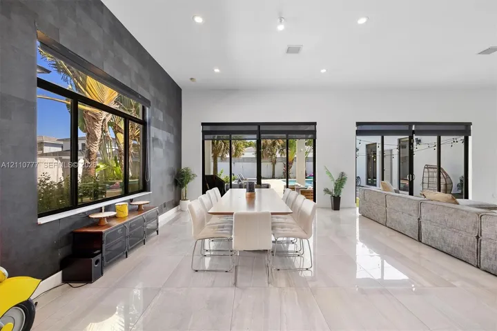 Spacious interior featuring large-format tile flooring, a charcoal-toned textured accent wall, recessed lighting, and multiple sliding glass door systems