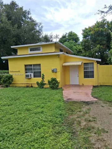 Stucco exterior featuring a low-pitched roofline, multi-level design, metal window awnings, and an attached privacy fence