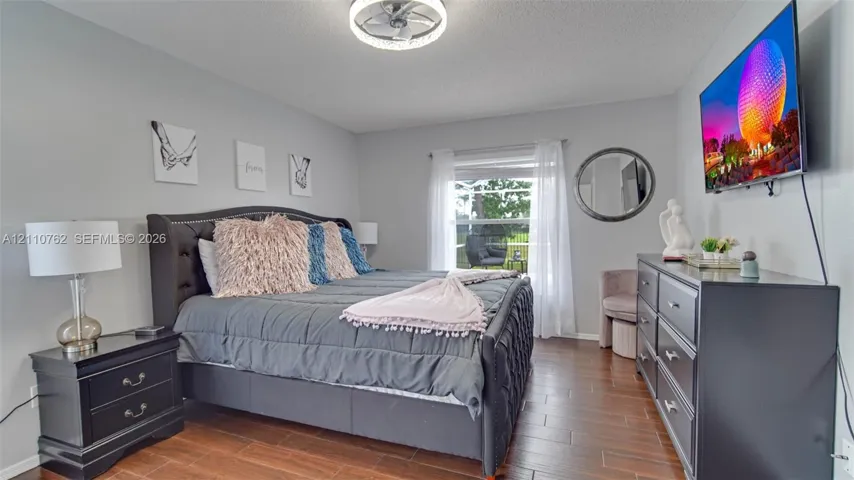 Wood-finish flooring, neutral wall tones, large window with natural light, and a modern ceiling-mounted light fixture