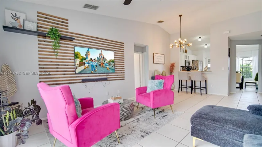 Living area featuring a horizontal wood-slat accent wall with a floating shelf, vaulted ceilings, and a multi-arm chandelier