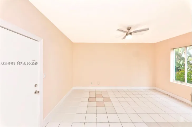 Neutral interior room featuring white tile flooring, a multi-blade ceiling fan with integrated lighting, and a single-pane window