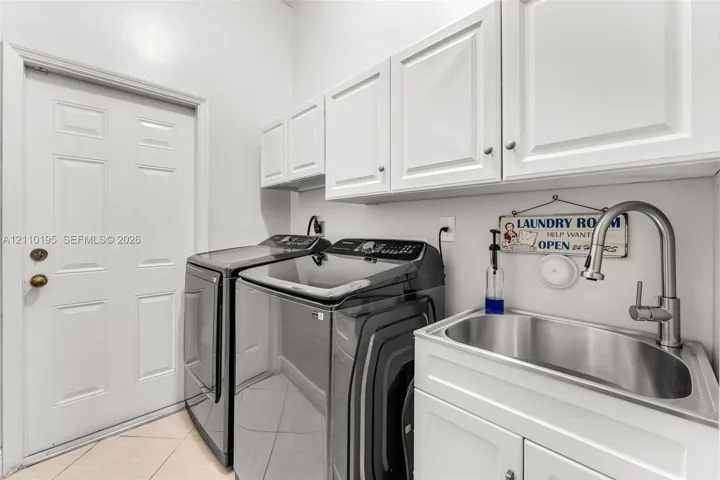 Laundry room featuring crisp white built-in cabinetry, an integrated stainless steel basin, and a high-arch pull-down faucet