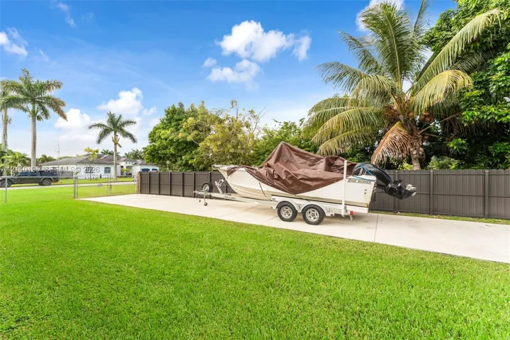 Expansive concrete pad, dark-finish privacy fencing, and manicured lawn