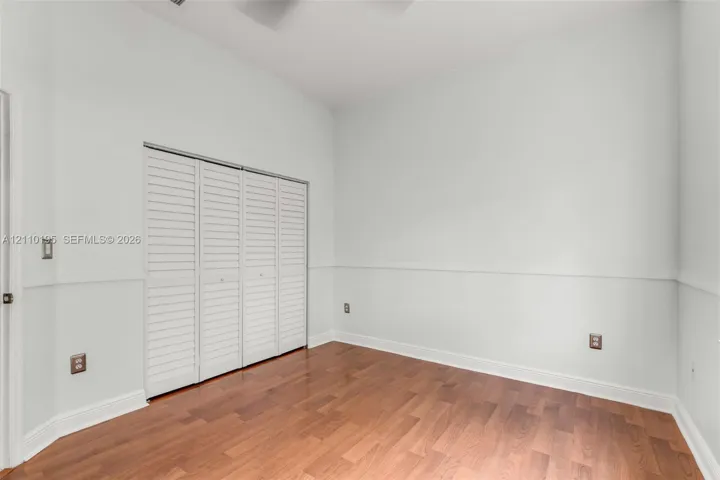 Interior space featuring wood-finish flooring, white louvered closet doors, and chair rail molding