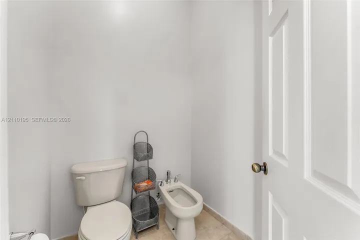 Ceramic-tile flooring, standard-height porcelain toilet, and pedestal bidet featuring chrome hardware