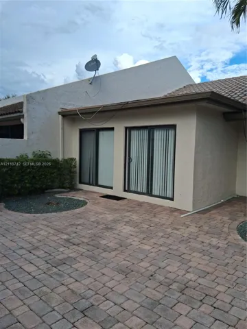 Exterior patio featuring stone paver flooring, stucco wall finish, tiled roofing, and dual sliding glass doors