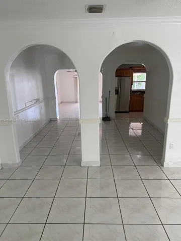 Interior featuring dual arched entryways with chair rail molding and light-toned ceramic tile flooring