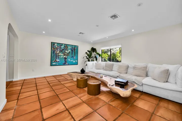 Living area featuring large-format terra cotta tile flooring, recessed lighting, and a neutral color palette