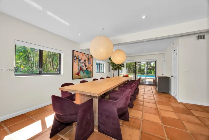 Dining area featuring terracotta tile flooring, recessed lighting, dual oversized spherical pendant fixtures, and large sliding glass doors
