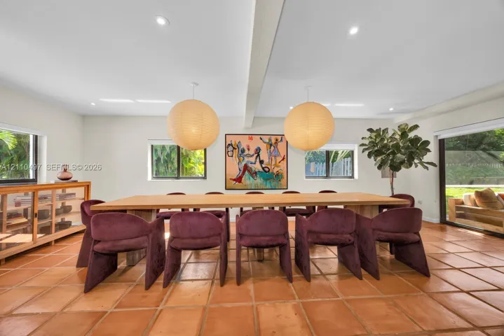 Terra cotta tile flooring, recessed ceiling lighting, oversized spherical pendant fixtures, a exposed ceiling beam, and dual sliding glass doors