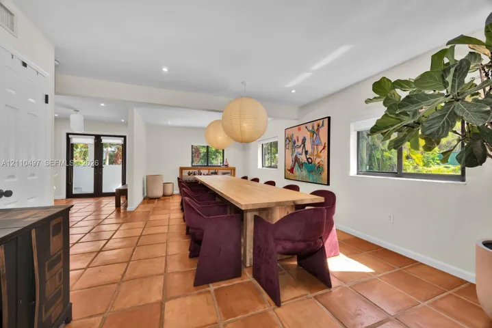Large-format terracotta tile flooring, dual oversized spherical pendant light fixtures, and expansive windows featuring dark-framed casings