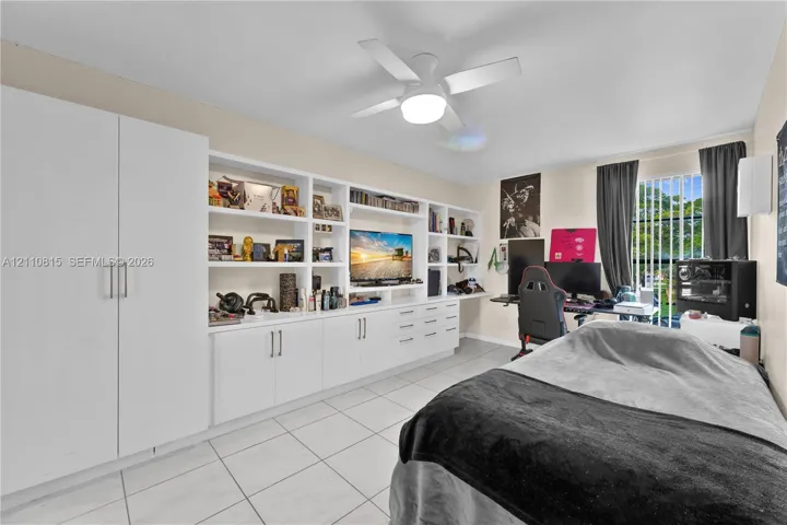 Wall-to-wall built-in cabinetry featuring white shaker-style doors, open display shelving, and integrated drawers, complete with tile flooring and a ceiling-mounted light fixture