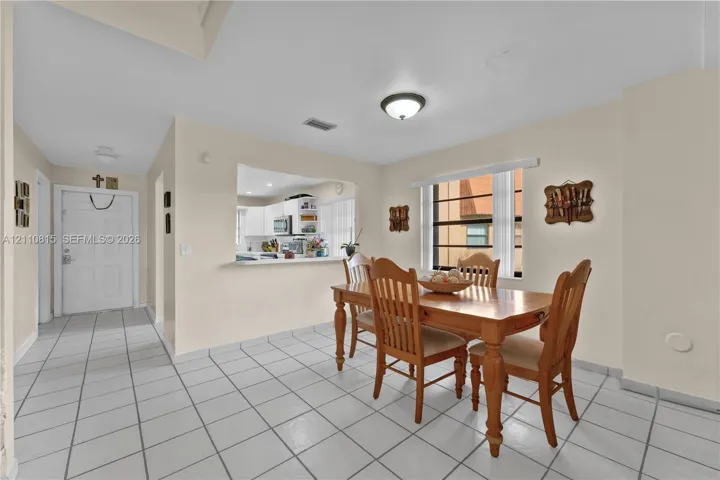 Interior space featuring large-format tile flooring, a pass-through window to the kitchen, and a window with horizontal blinds
