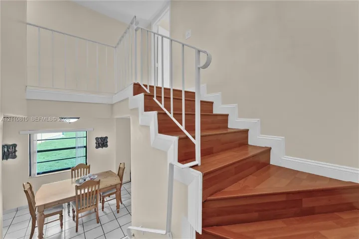 Staircase featuring wood-finish treads, white painted risers, and a white metal railing