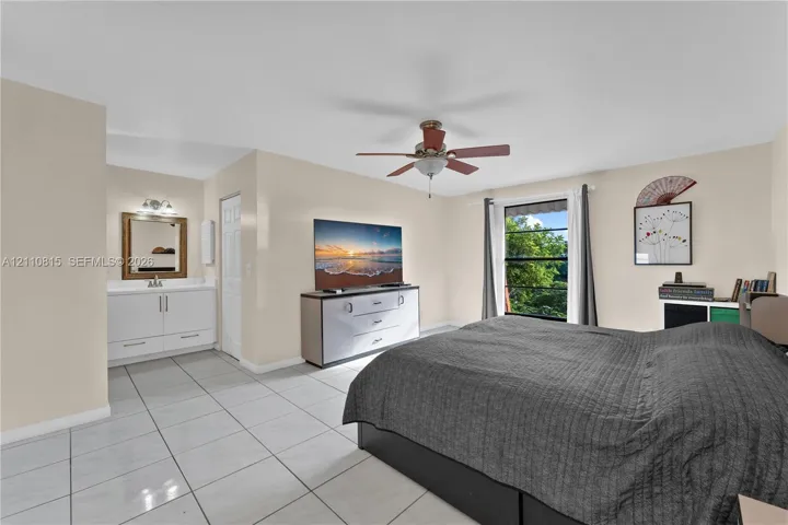 Room featuring tile flooring, a built-in vanity with a framed mirror, and a ceiling fan with integrated lighting