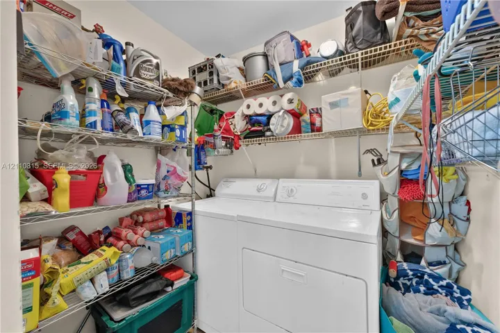 Laundry area featuring white top-load washer and dryer with multi-level wire shelving