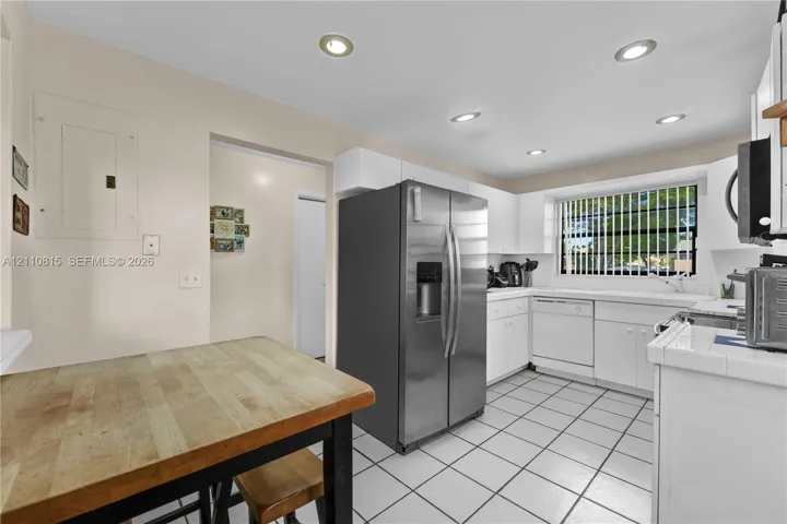 Kitchen featuring white cabinetry, stainless steel side-by-side refrigerator, recessed lighting, and tile flooring