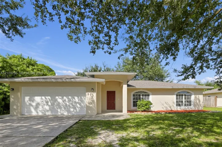 Single-story exterior featuring light-toned stucco siding, an attached two-car garage, an arched entryway, and multiple windows with decorative arched transoms