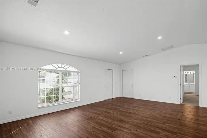 Vaulted ceilings, wood-finish flooring, recessed lighting, and a window featuring an arched transom