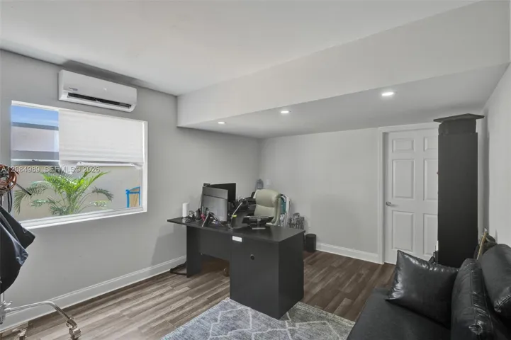 Interior room featuring wood-finish flooring, recessed lighting, a wall-mounted ductless mini-split unit, and a single-panel interior door