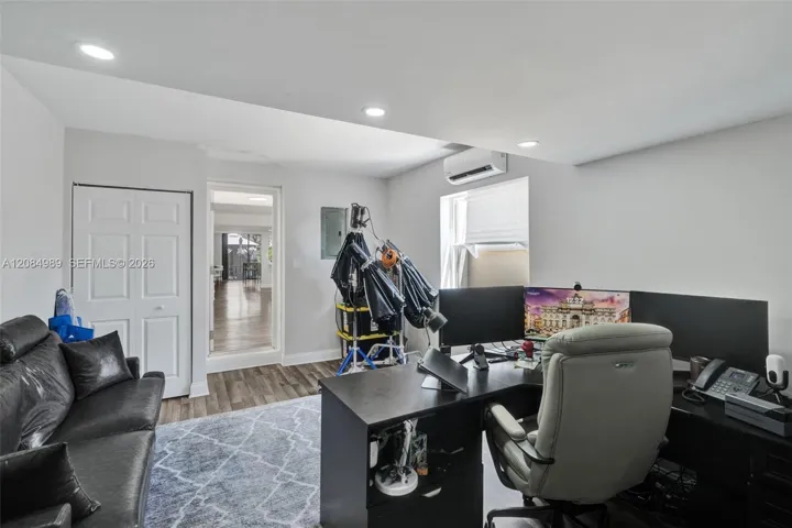 Wood-finish flooring, recessed lighting, wall-mounted climate control unit, and a six-panel closet door