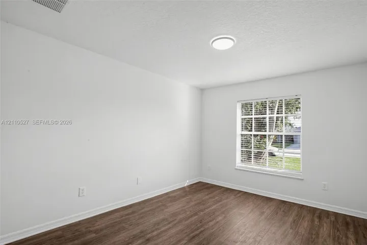 Interior room featuring wood-finish flooring, a multi-pane window, and a ceiling-mounted light fixture