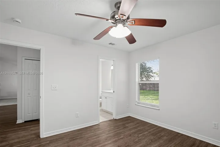 Room featuring wood-finish flooring, a multi-blade ceiling fan with integrated lighting, and a window with horizontal blinds