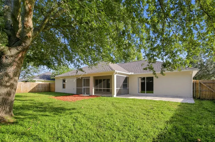 Backyard featuring a screened-in porch, concrete patio, mature trees, and wood privacy fencing