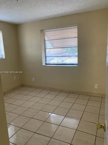 Room featuring light-toned tile flooring, matching tile trim, and dual windows