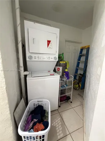 Stacked laundry unit on tile flooring featuring a six-panel door