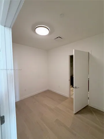 Neutral wall tones, wood-finish flooring, and a flush-mount ceiling light fixture